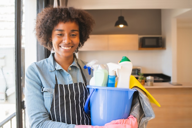 Free photo afro woman holding a bucket with cleaning items.