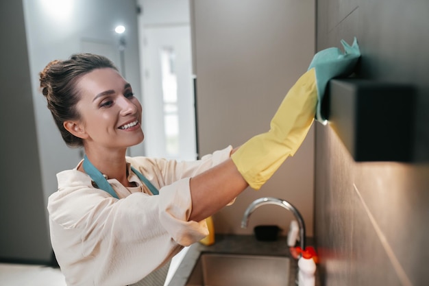 Free photo chores. young dark-haired woman cleaning the surfaces in the kitchen