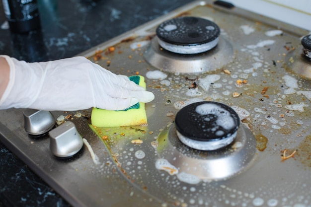 Photo domestic female hand wearing gloves cleaning dirty stove after cooking using sponge for washing woman housewife enjoying daily household closeup top view