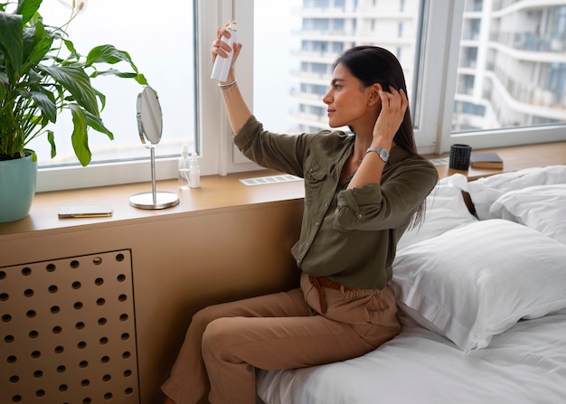 Free photo side view woman using dry shampoo at home