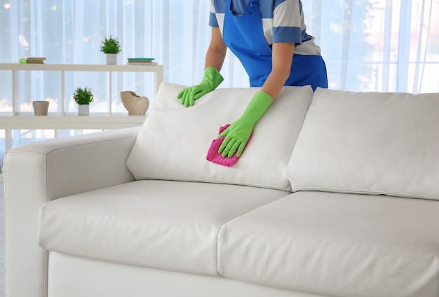 Photo woman cleaning couch with duster at home