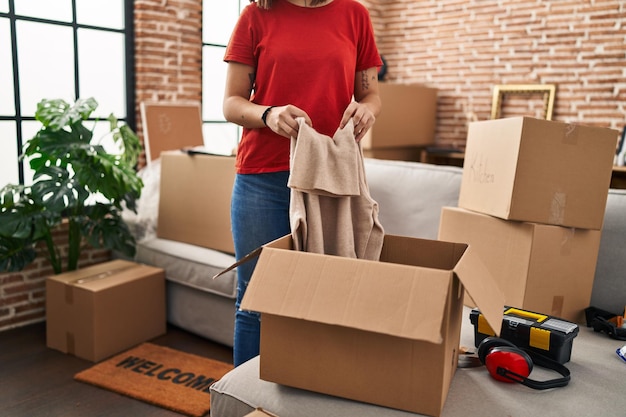 Free photo young beautiful hispanic woman unpacking cardboard box at new home