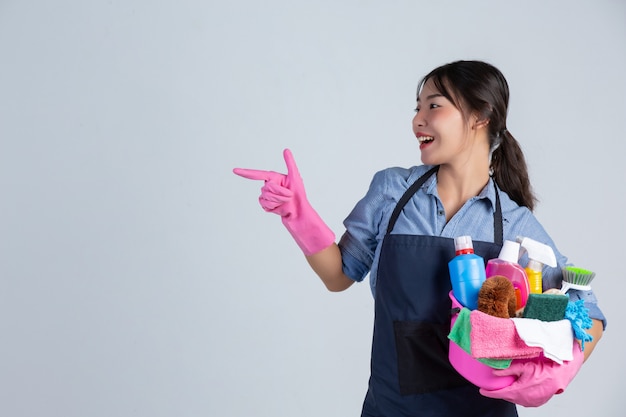 Free photo young housewife is wearing yellow gloves while cleaning with the product of clean on white wall.