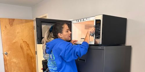 BraBos Cleaning team member cleaning a microwave in an office kitchen