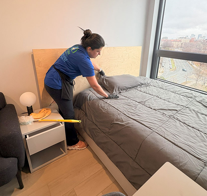 Brabos Cleaning staff member making a bed and cleaning a bedroom in a Boston home