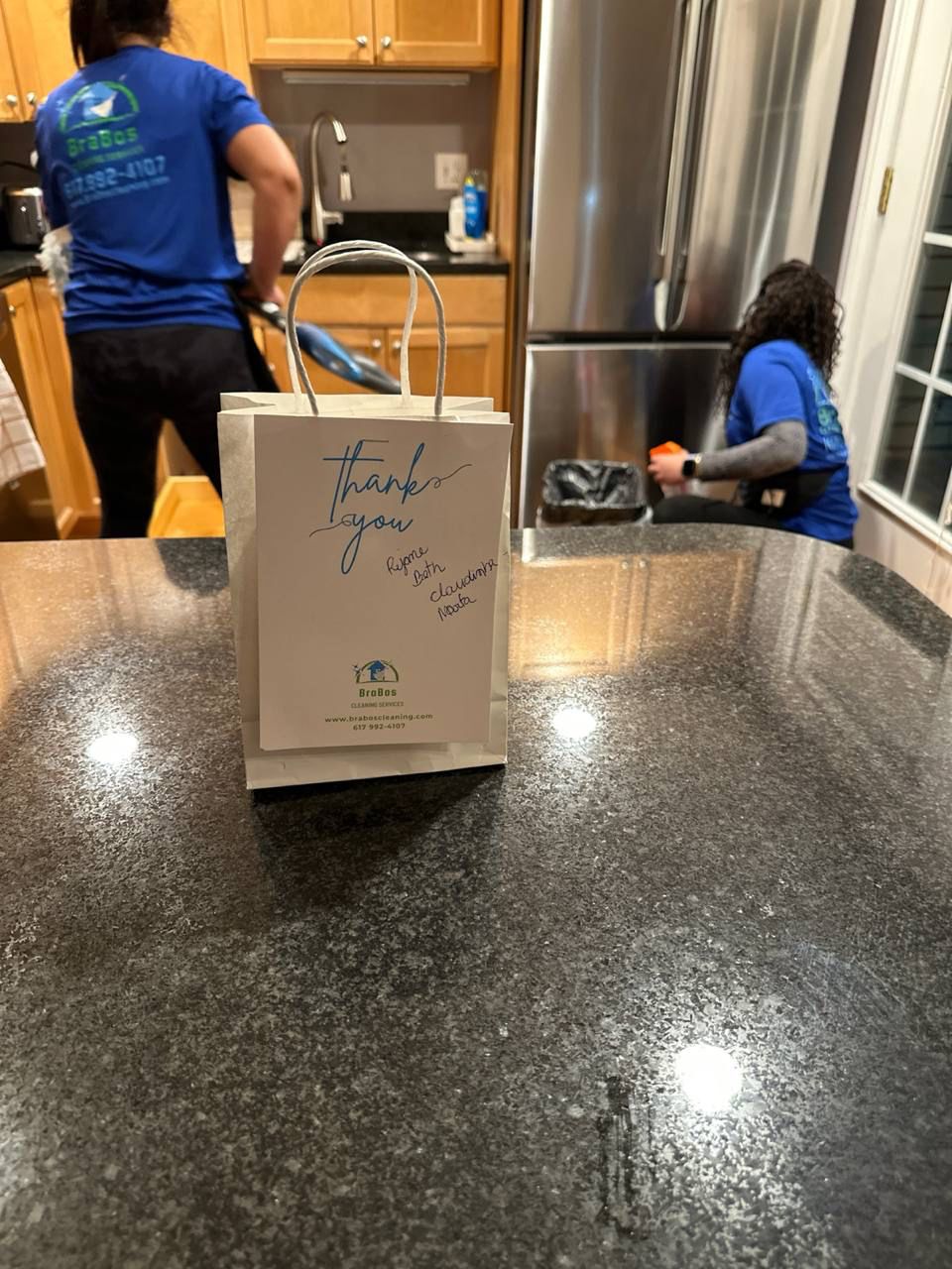 Two BraBos Cleaning staff members performing Boston maid duties with a thank-you goody bag from a happy client